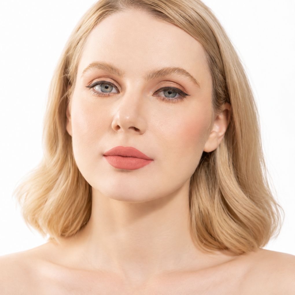 Model wearing Oplenza Signature Longwear Matte Lipstick in 02 Peche, showing nude peach matte lips.