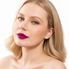 Model wearing Oplenza Signature Longwear Matte Lipstick in 10 Aubergine, showing vibrant magenta-purple lips color, set against a clean white background.