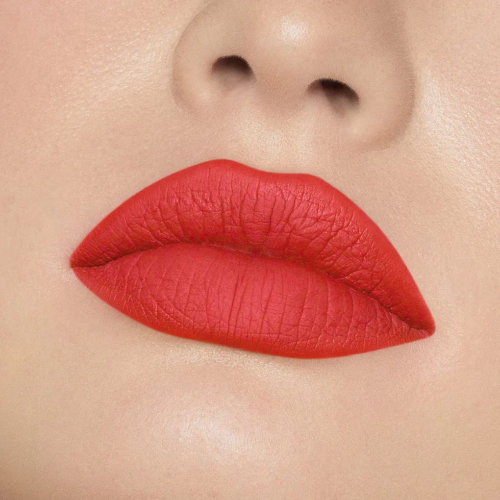 Close-up of model wearing oplenza Icon Matte Lipstick in shade 24 Coral Icon, best matte lipstick for dry lips