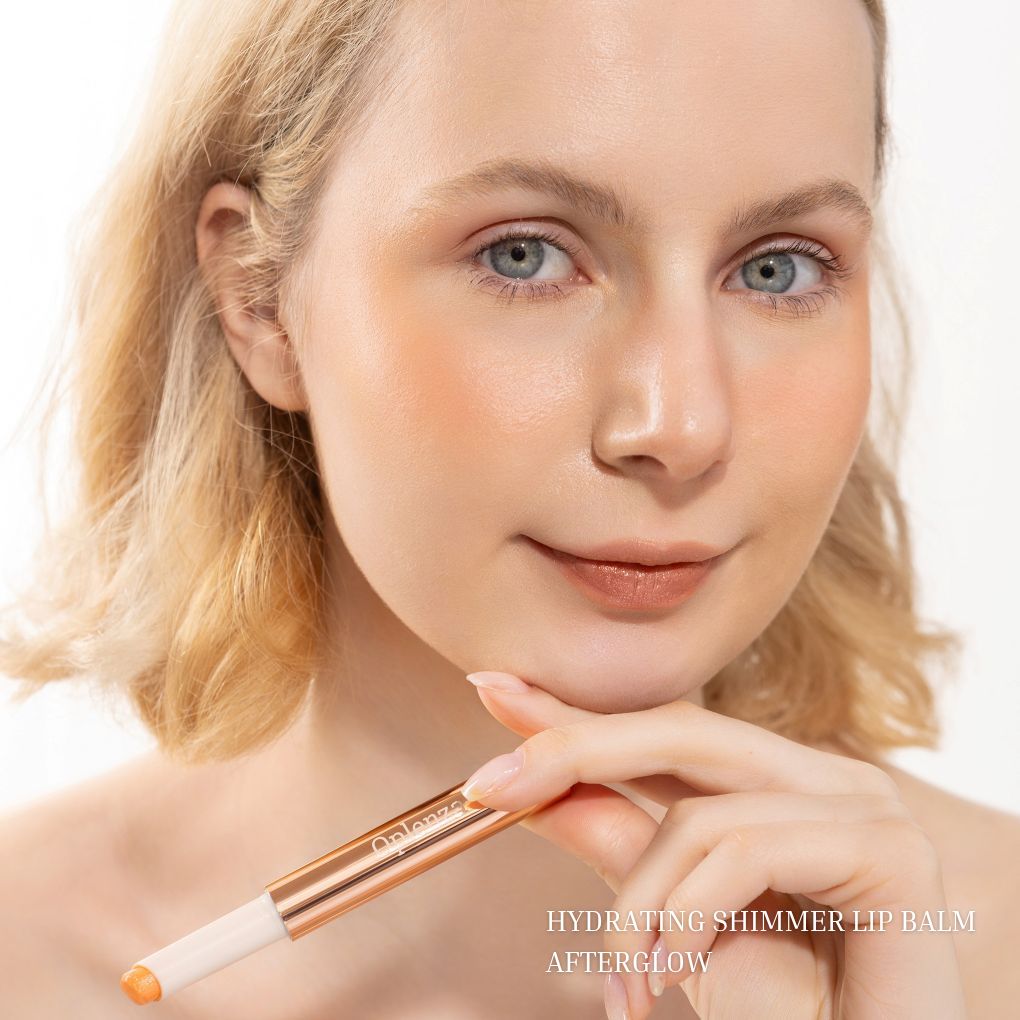 Model wearing Oplenza Hydrating Shimmer Lip Balm in Afterglow with luminous shimmer finish