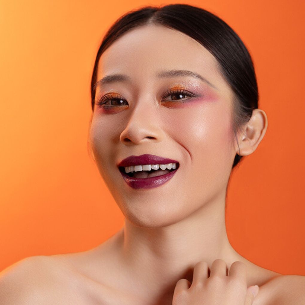 Model wearing and showcasing the bold color of the vegan, cruelty-free Oplenza matte liquid lipstick in the shade Bliss