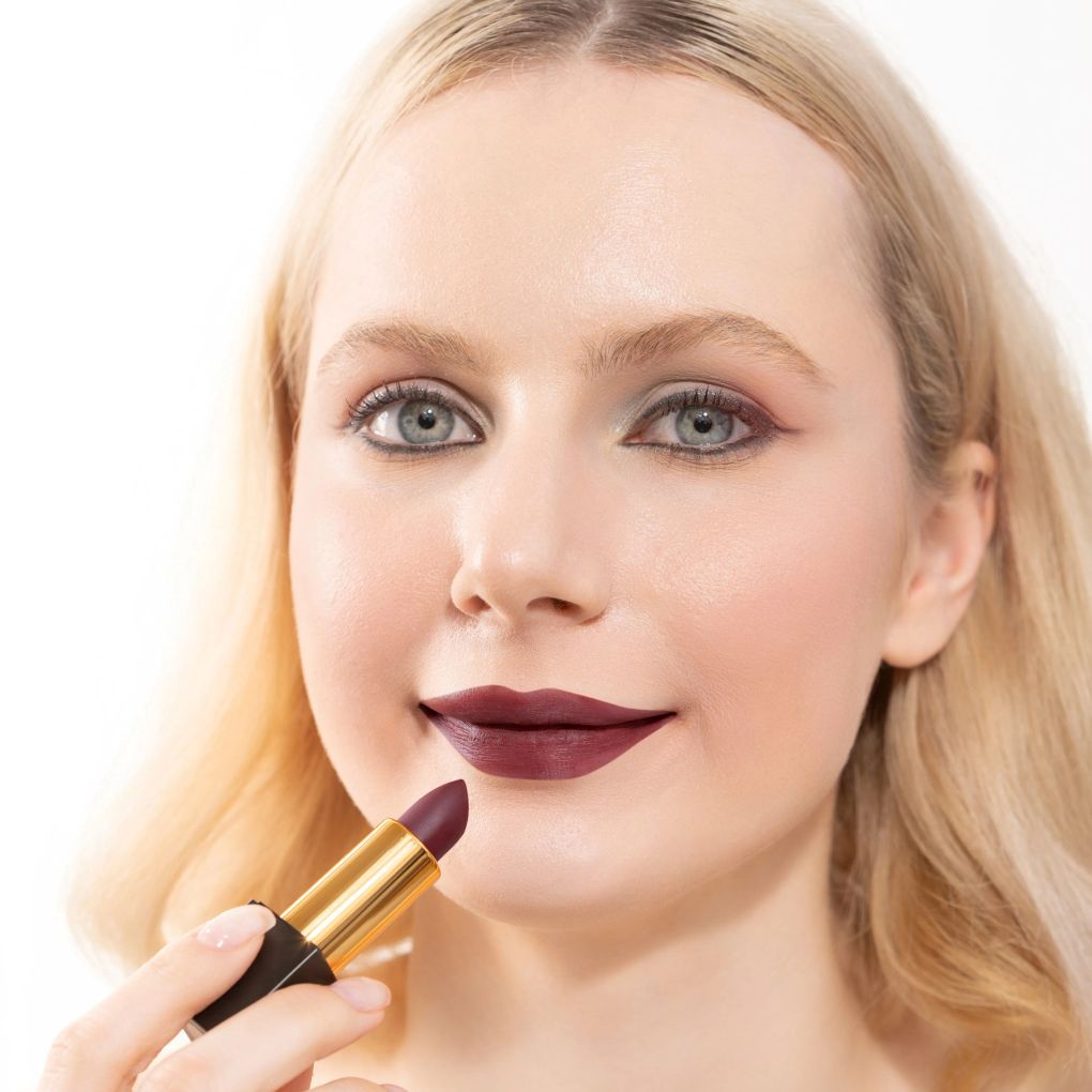 Woman applying and showcasing the effects of the best cruelty-free Oplenza Signature Matte Lipstick in shade Bold