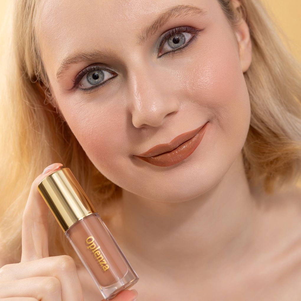 A woman wearing and showcasing the best cruelty-free, vegan, shiny and hydrating lip gloss in shade Champagne
