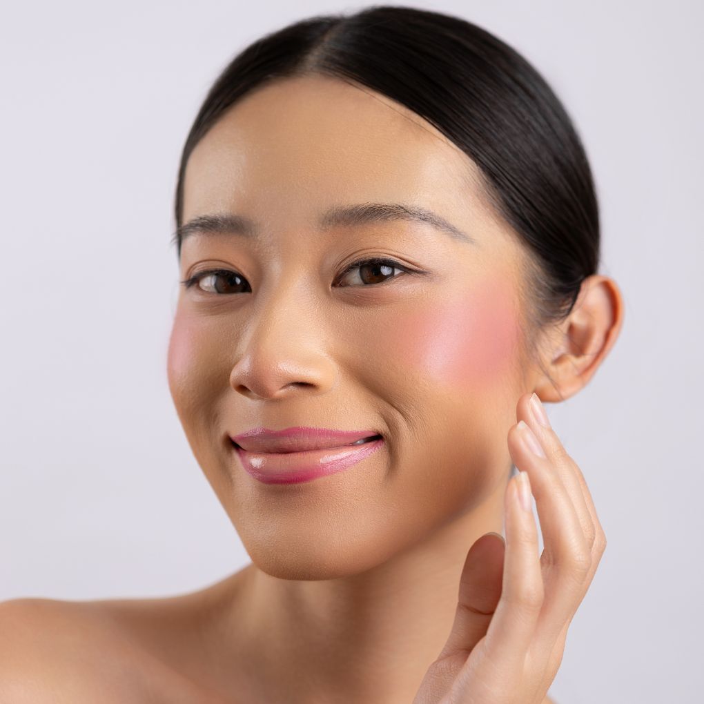 A woman wearing on her cheek Oplenza highly pigmented, bold color dewy Blush Stick in shade Composed