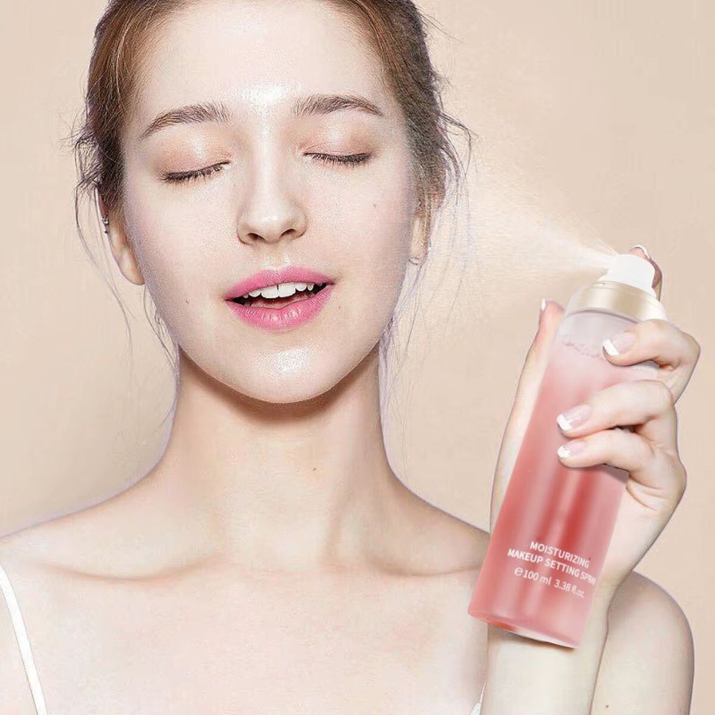 Woman holding and spraying oplenza setting sprays against a beige background