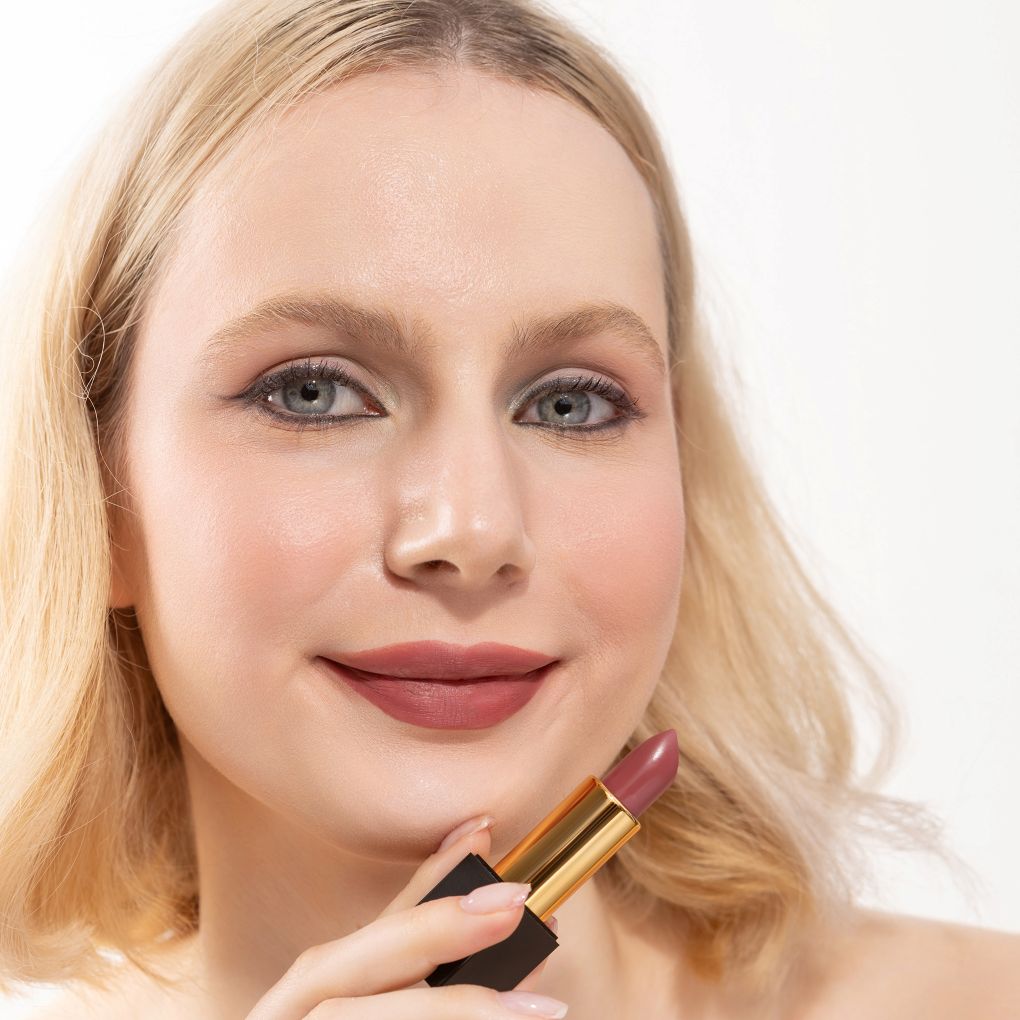 Woman applying and showcasing the effects of the best cruelty-free Oplenza Signature Matte Lipstick in the Loving shade.