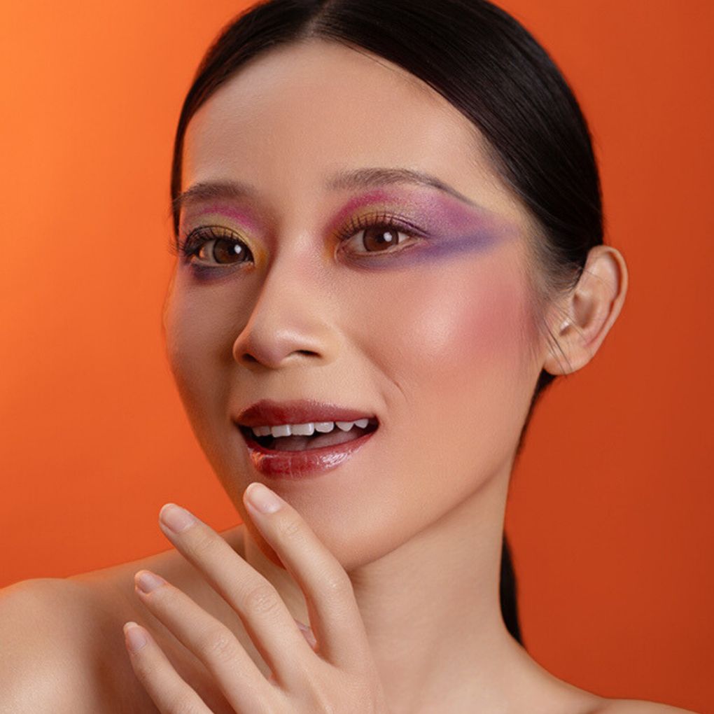 A woman wearing and presenting the beautiful effect of Oplenza's Hydrating Shimmer Glossy Lip Balm in shade Macaron