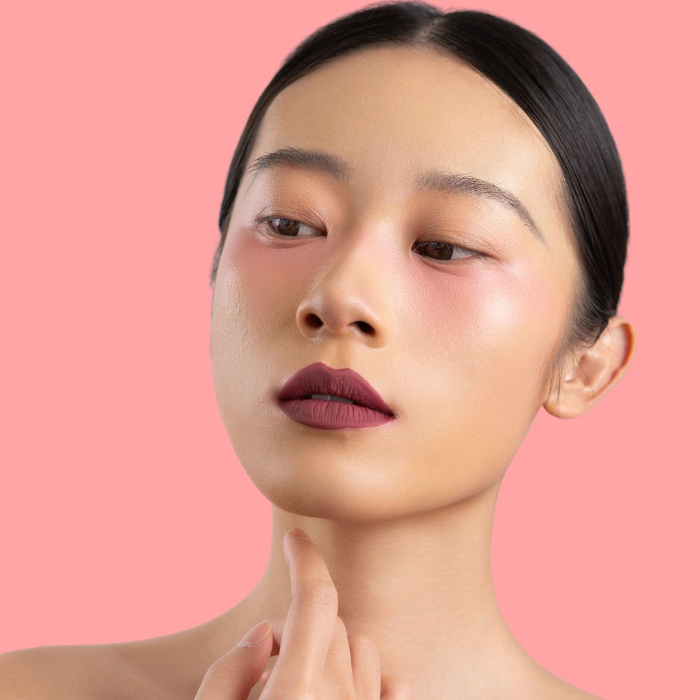 Model wearing and showcasing the bold color of the vegan, cruelty-free Oplenza matte liquid lipstick in the shade Mauve Luxe