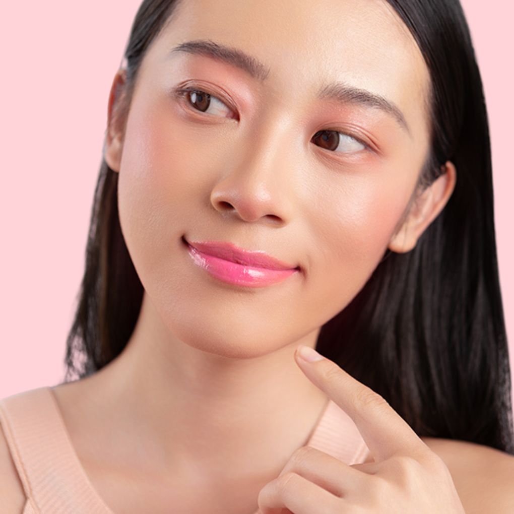 A woman wearing and showcasing the best cruelty-free, vegan, shiny and hydrating lip gloss in shade Petal