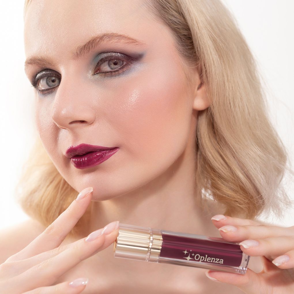 Woman holding a lip gloss with 'Oplenza' branding against a white background