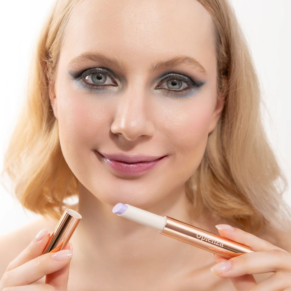 A woman wearing and presenting Oplenza's Hydrating Shimmer Glossy Lip Balm in shade Sugar