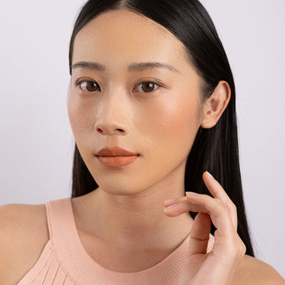 Model wearing and showcasing the bold color of the vegan, cruelty-free Oplenza matte liquid lipstick in the shade Terra