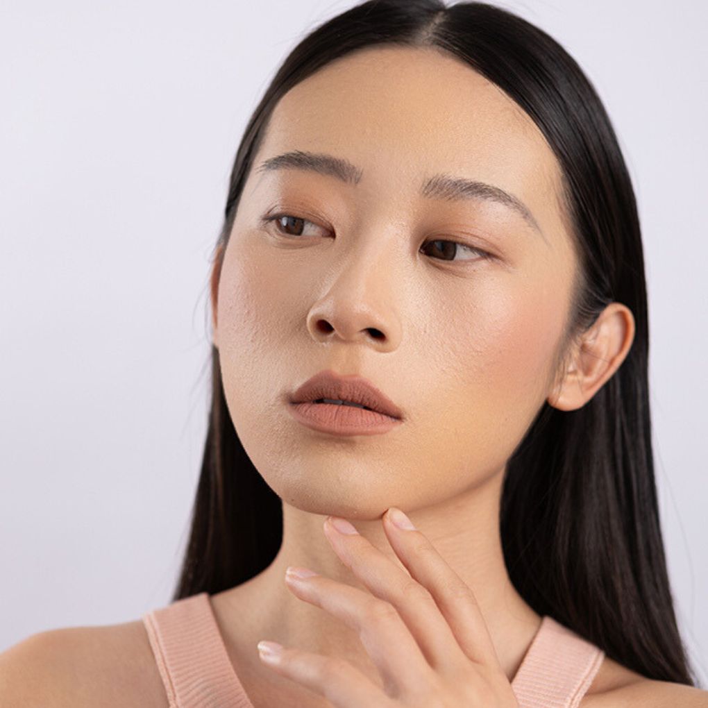 A Woman wearing and showcasing the effect of the elegant cruelty free Oplenza Signature Velvet Liquid Lipstick in the color Vlevet Nude