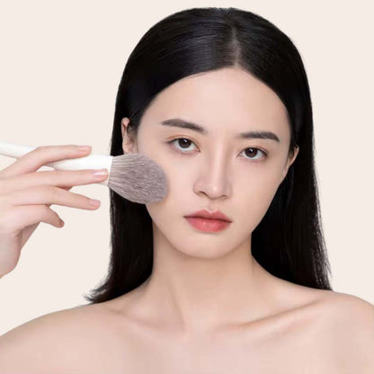 Woman using and showcasing oplenza foundation brush